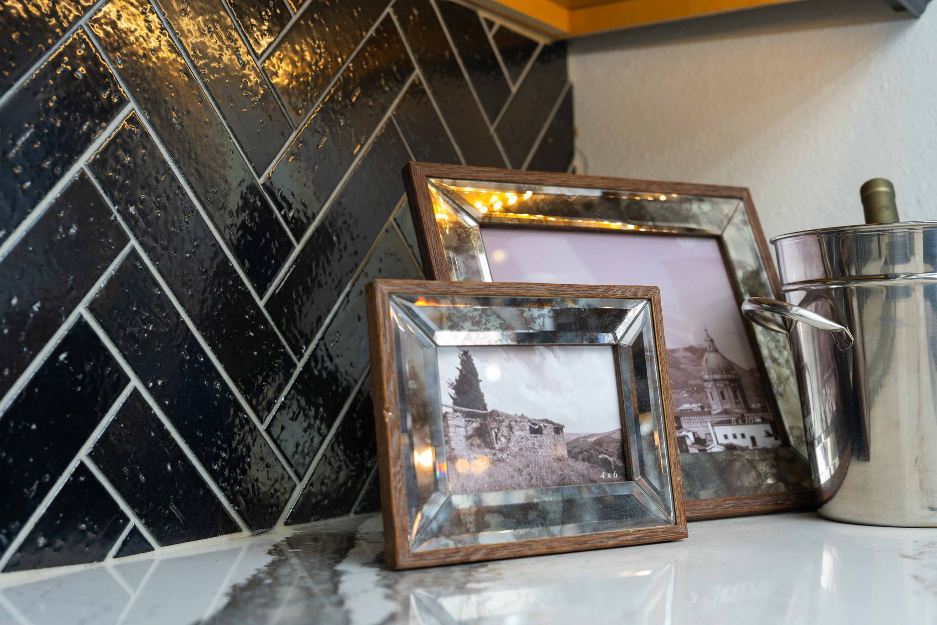 Three picture frames are sitting on a counter in a kitchen.