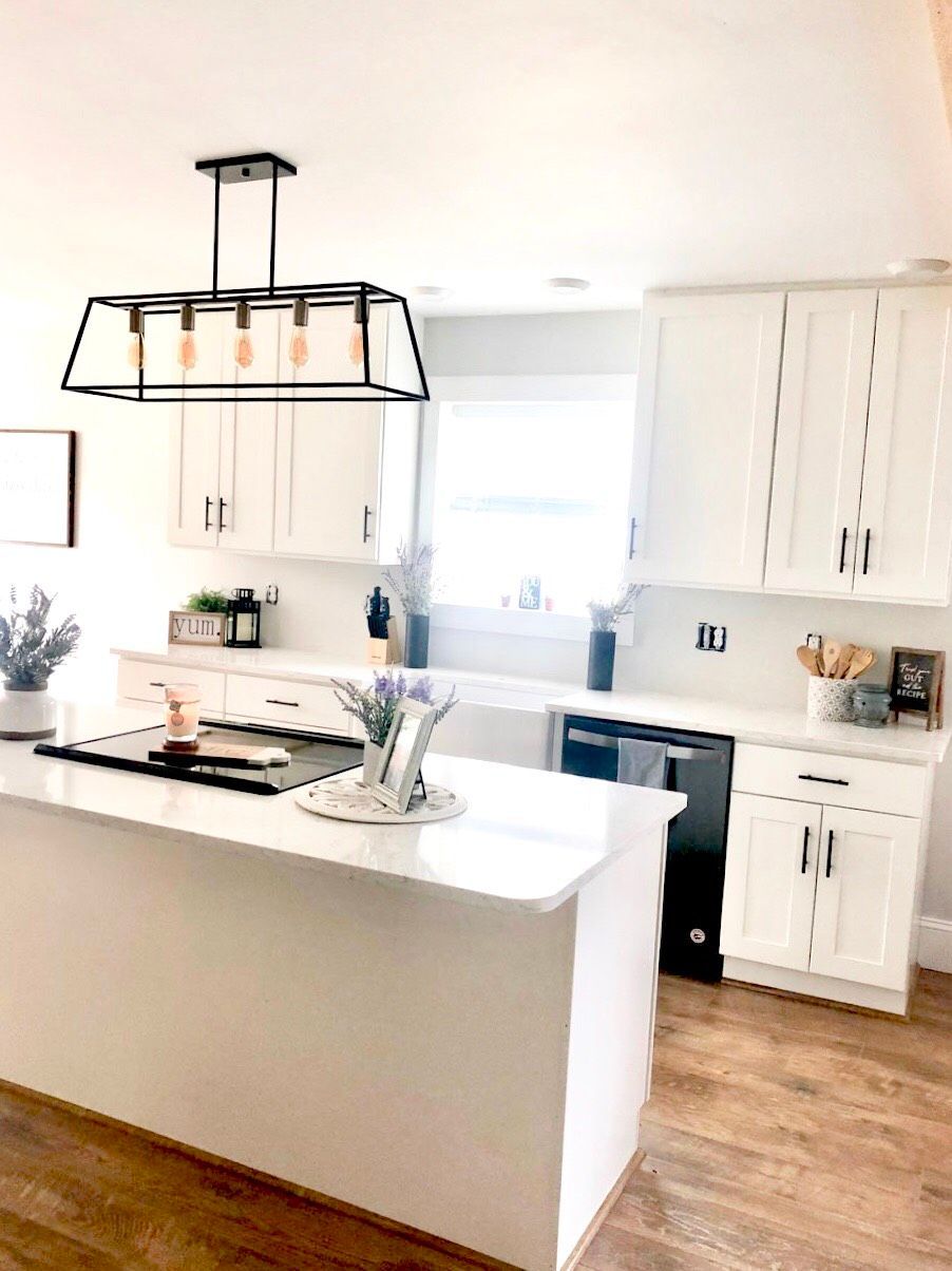 A kitchen with white cabinets and a large island in the middle.