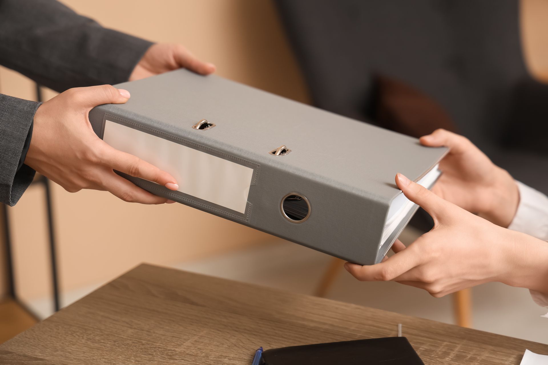 Hands exchanging a gray shoebox across a table