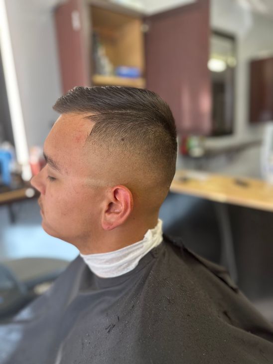 A man is getting his hair cut at a barber shop.