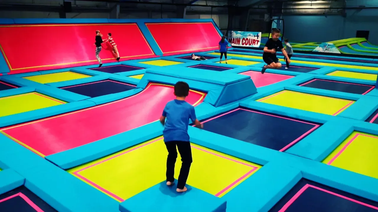 Children jumping on colorful trampolines at an indoor trampoline park.