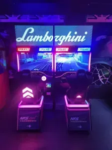 Two Lamborghini racing arcade games with pink and blue lights.