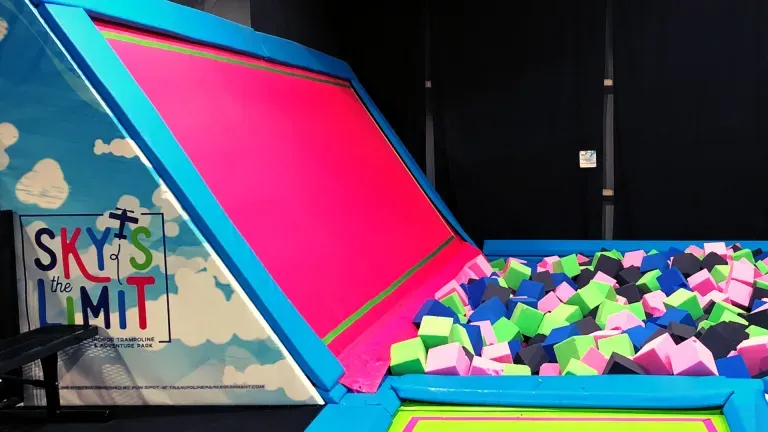 Trampoline pit with pink, blue, green foam cubes; Sky's the Limit logo in background.