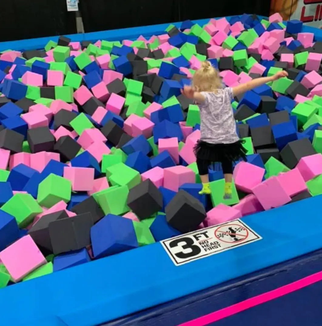 Child jumping into a colorful foam pit.