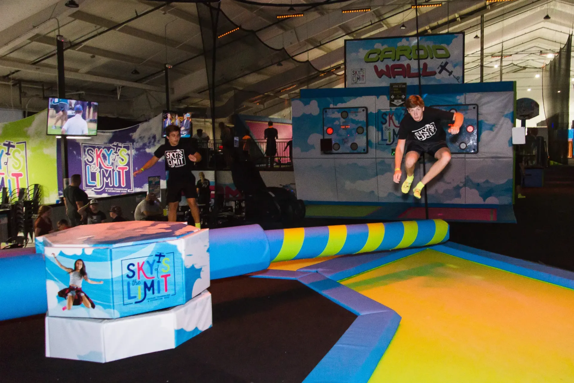 Two people jumping obstacles at an indoor trampoline park.