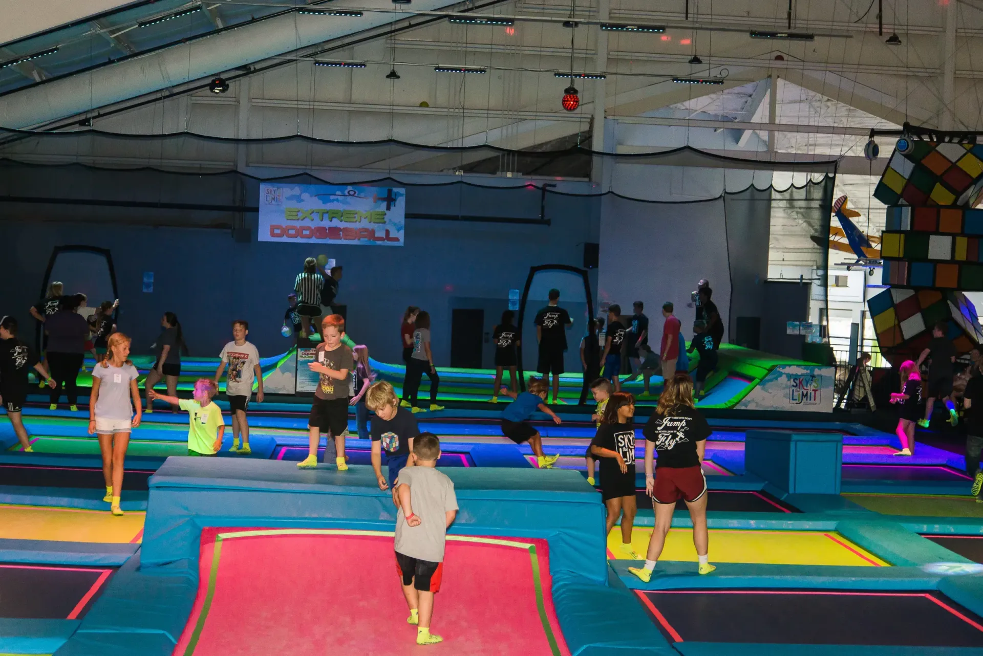 Children jumping on trampolines in a large, brightly lit indoor play area.