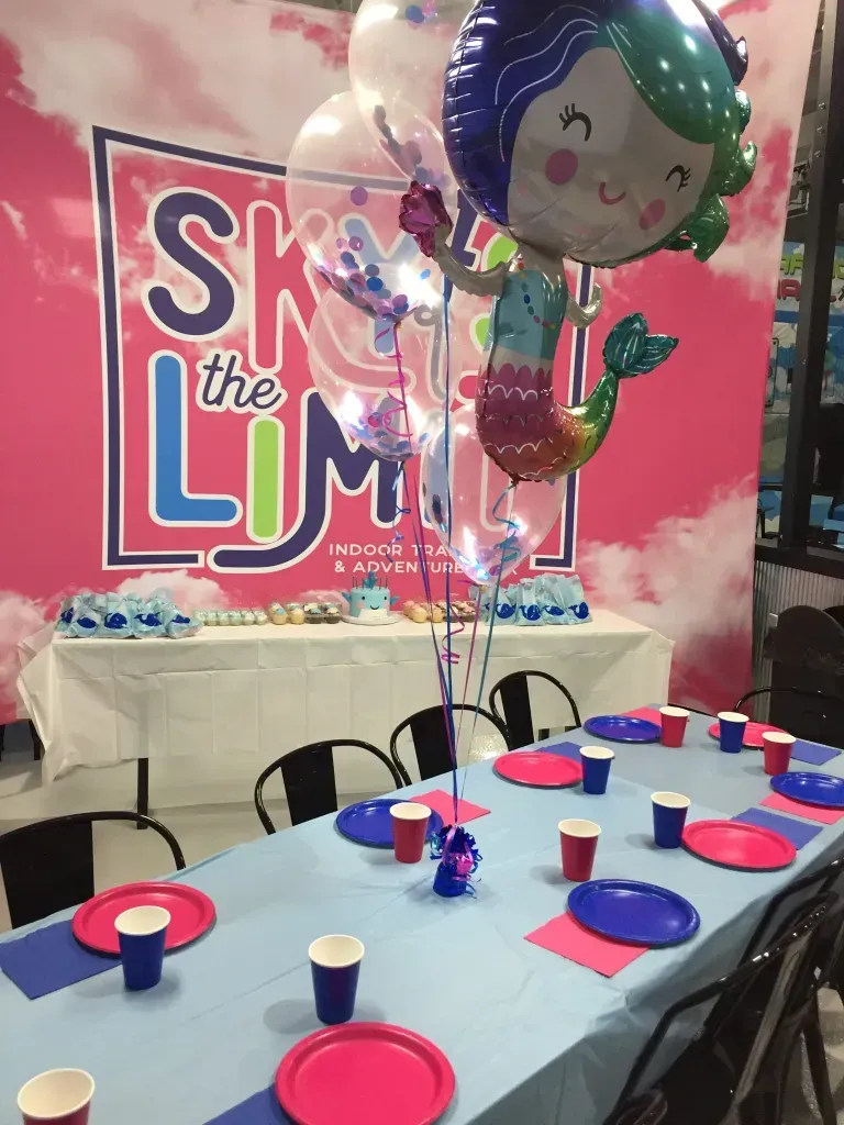 Mermaid-themed party table with decorations and mermaid balloon in front of a