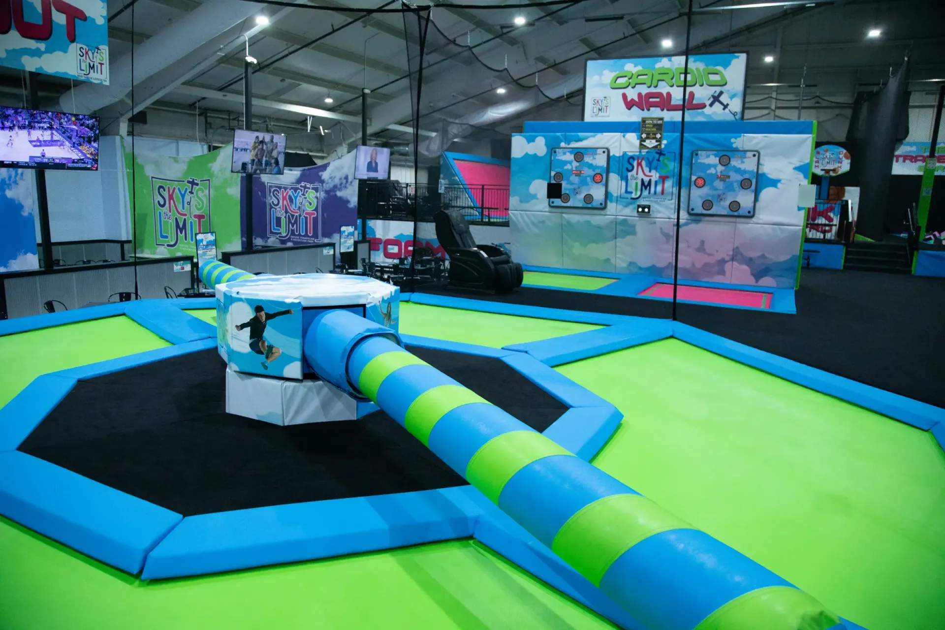 Indoor trampoline park with blue and green padded structures.