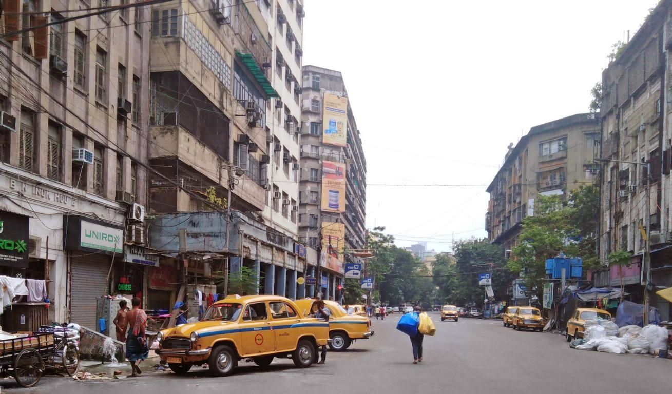 Blick zwischen die Häuserschluchten Kalkuttas, gelbe Taxis stehen am Straßenrand