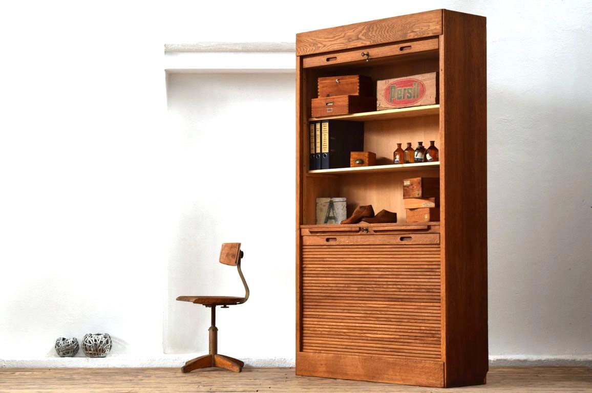 großer antiker Rollladenschrank neben einem Stuhl