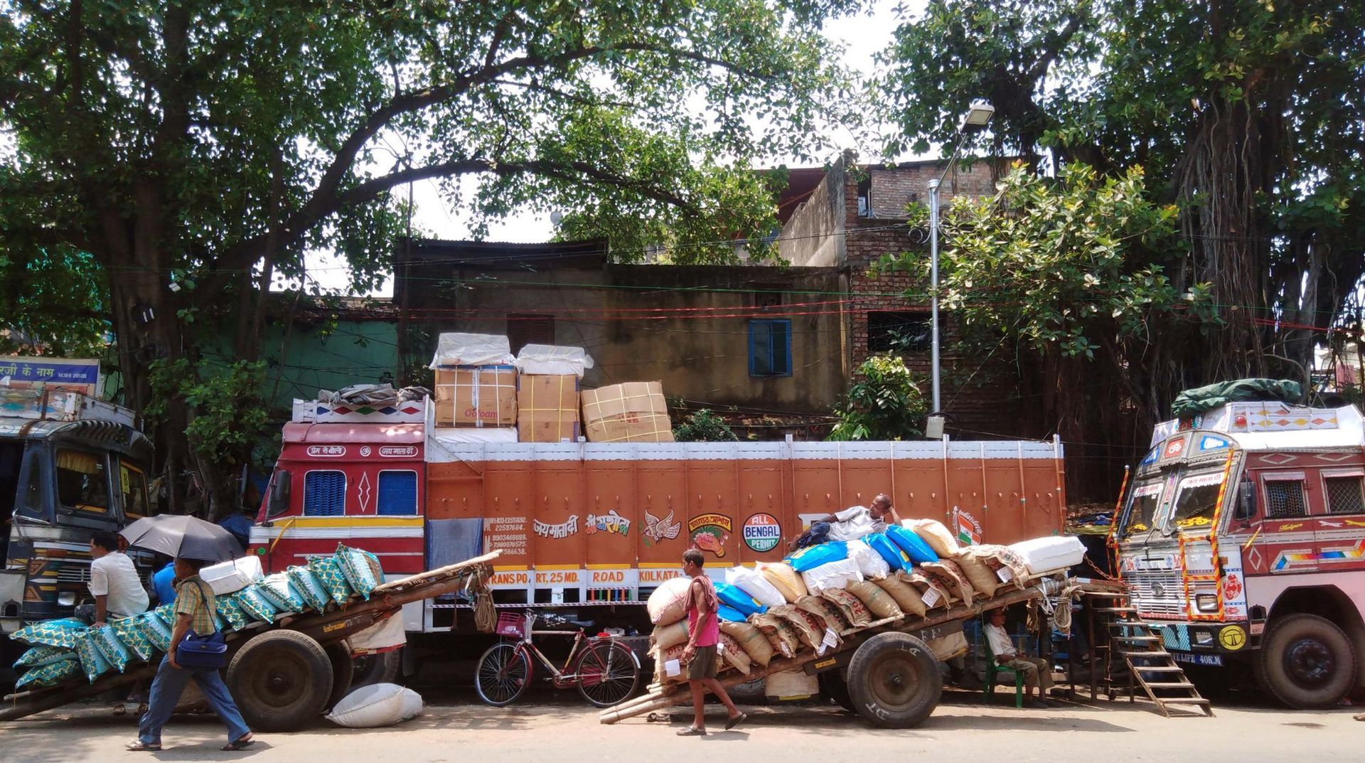 Straßenbild in Kalkutta, indische Trucks werden von Arbeitern beladen