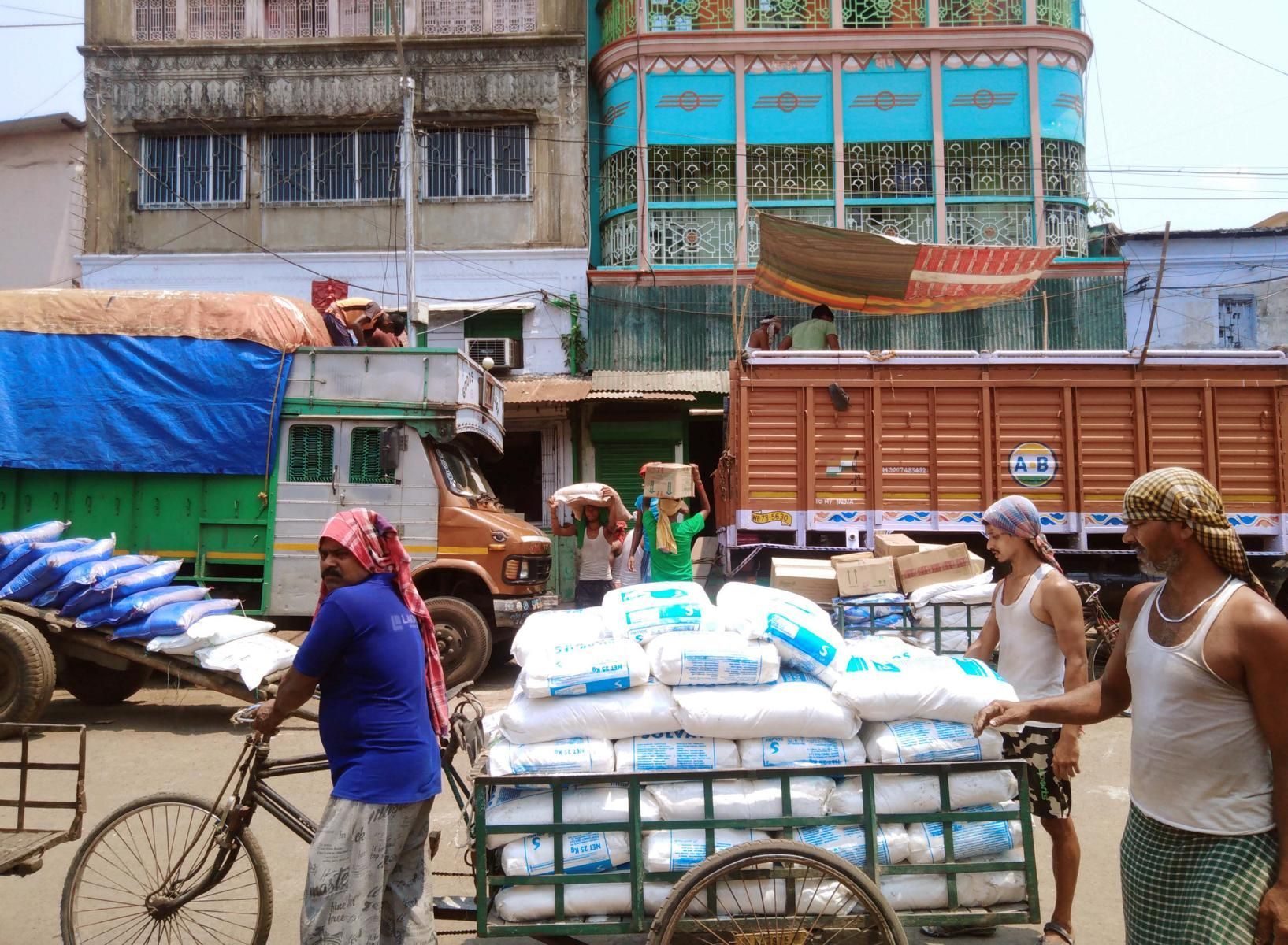 Burra Bazar Kalkutta, Arbeiter tragen Säcke auf ihrem Kopf, über LKW sind Tücher gespannt