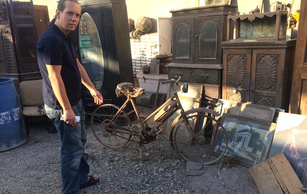 ein altes Fahrrad, daneben Bilder von den Kabinenwänden aus Kreuzfahrtschiffen von den Abwrackwerften bei Alang