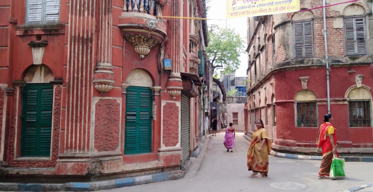 Alte Gebäude in Kalkutta, auf der Straße laufen Frauen mit traditioneller Bekleidung