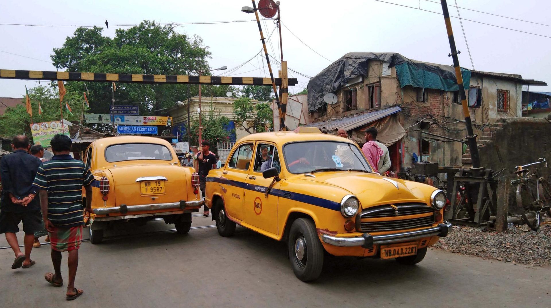 ein Bahnübergang am Blumenmarkt in Kalkutta wird von zwei Taxis überquert 