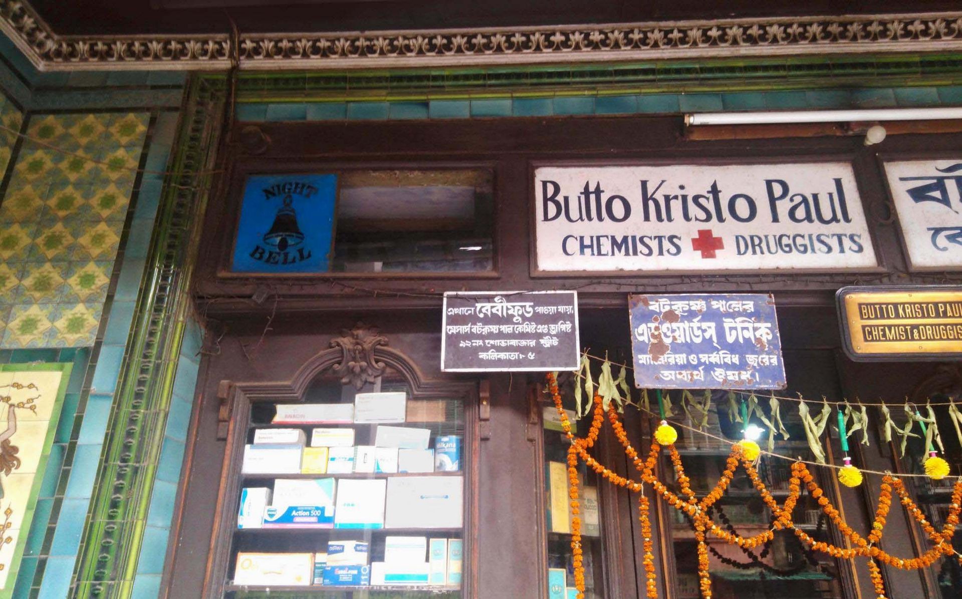 frische Blumen über dem Eingang der Apotheke Butto Kisto Paul in Kalkutta
