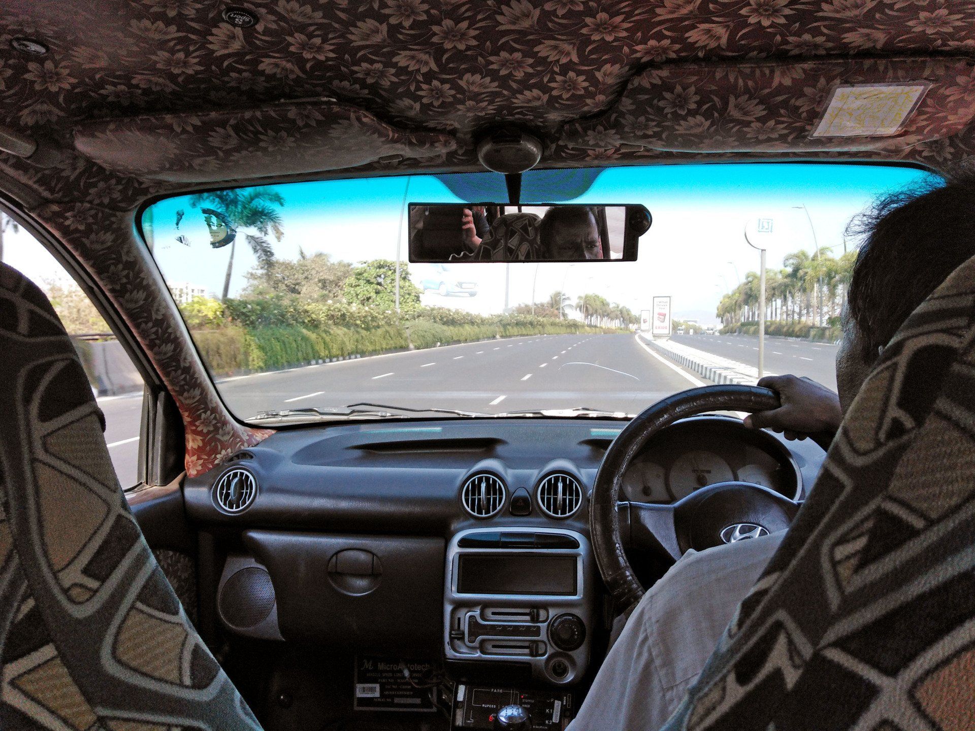 Blick auf die Straße aus einem farbenfroh gestaltetem Taxi auf dem Weg zum Flughafen Mumbai