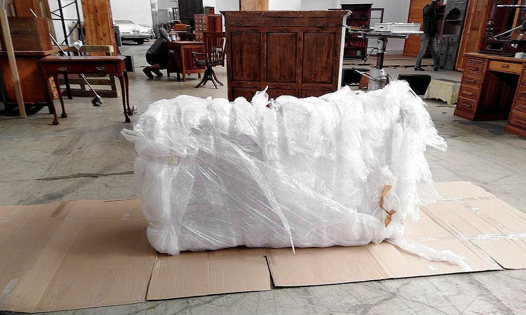 Verpackung und Vorbereitung eines antiken Schubladenschrankes für den internationalen Transport, liegend in alter Luftpolsterfolie eingepackt