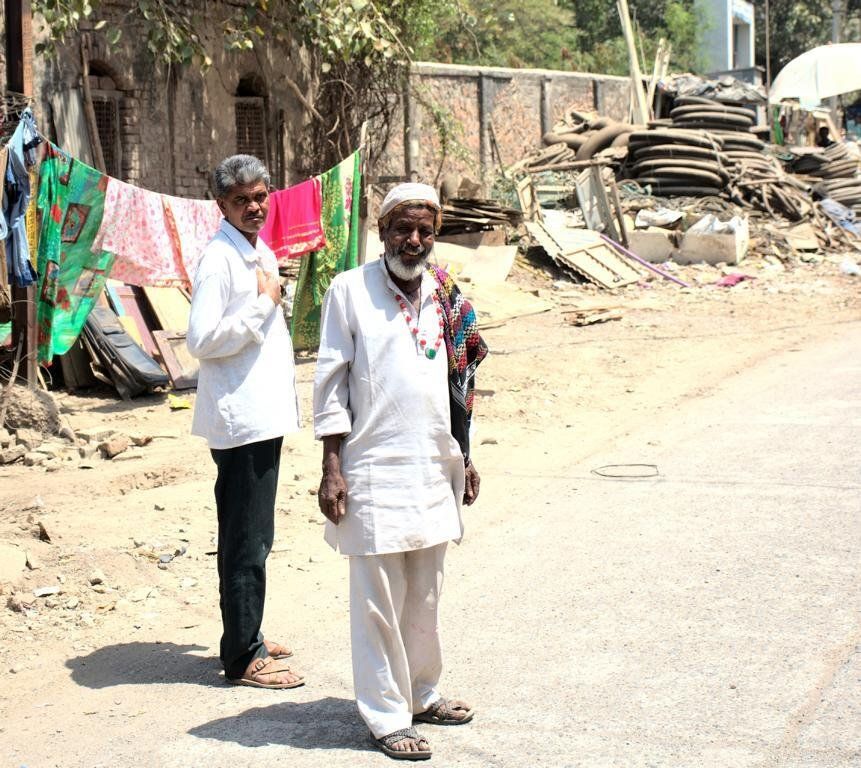 zwei indische Arbeiter in der Nähe der Abwrackwerften bei Alang Indien, Schiffsschrott im Hintergrund