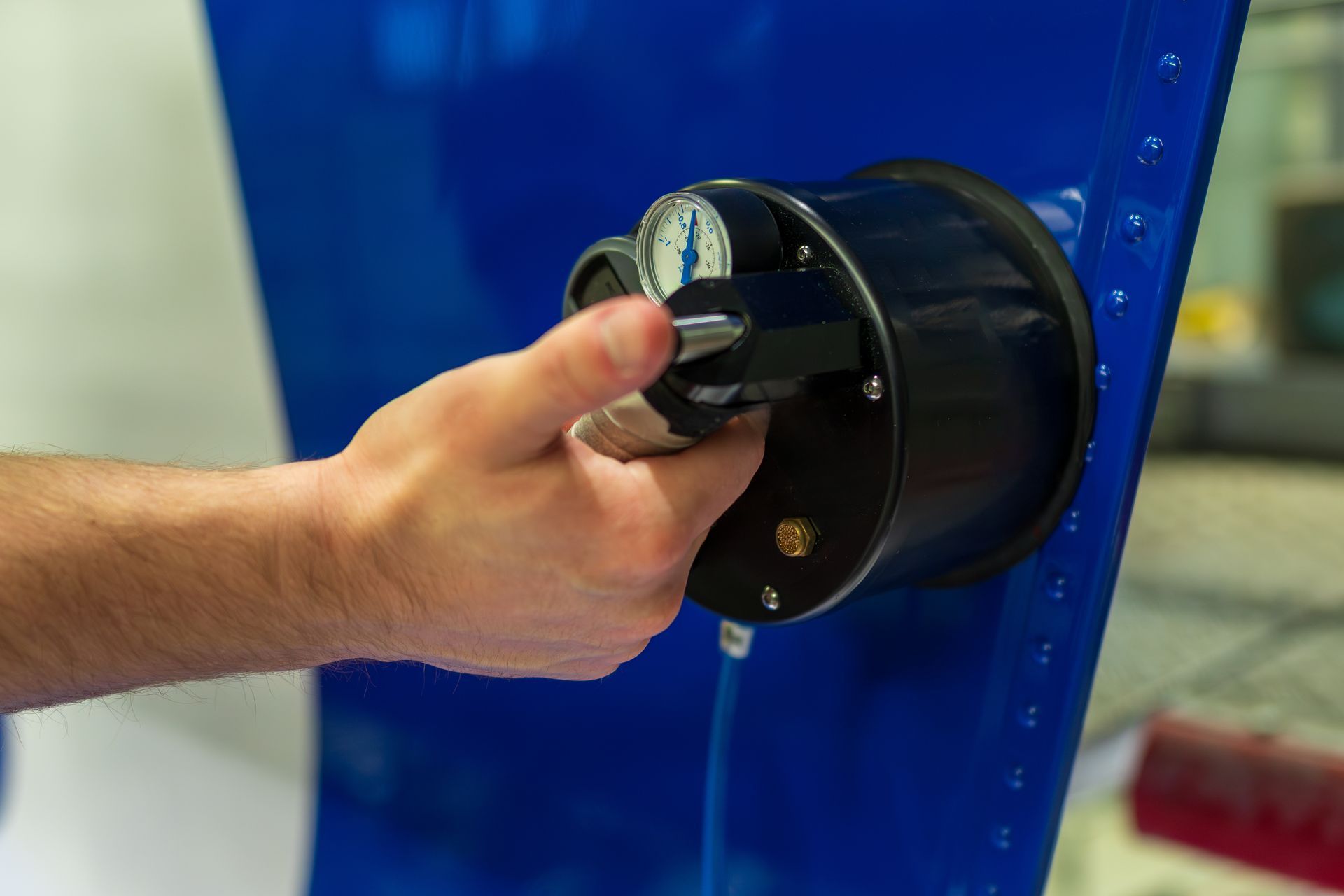 An engineer's hand is holding a pressure gauge instrument while testing structural integrity.