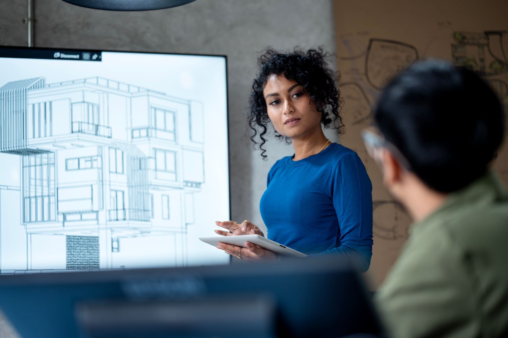 Residential structural engineer presenting building blueprint during team planning session.