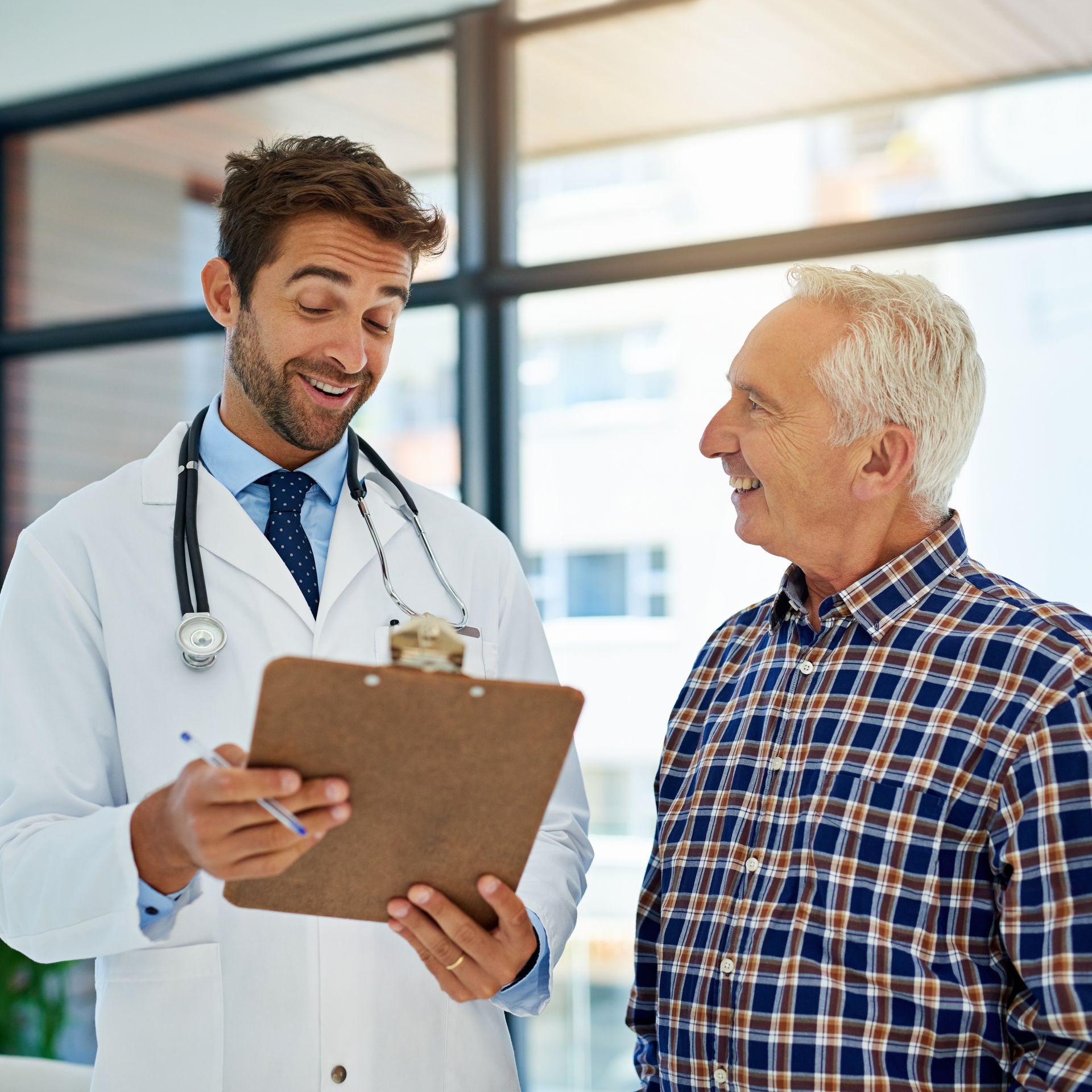 A smiling doctor in a lab coat with a stethoscope around his neck.