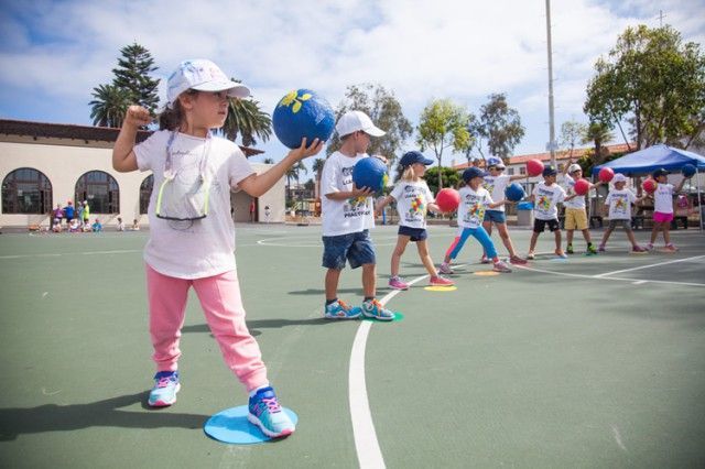 A group of children are playing with balls on a court.