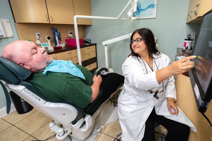 Dentist showing x-ray to patient in dental chair, in a dental office.
