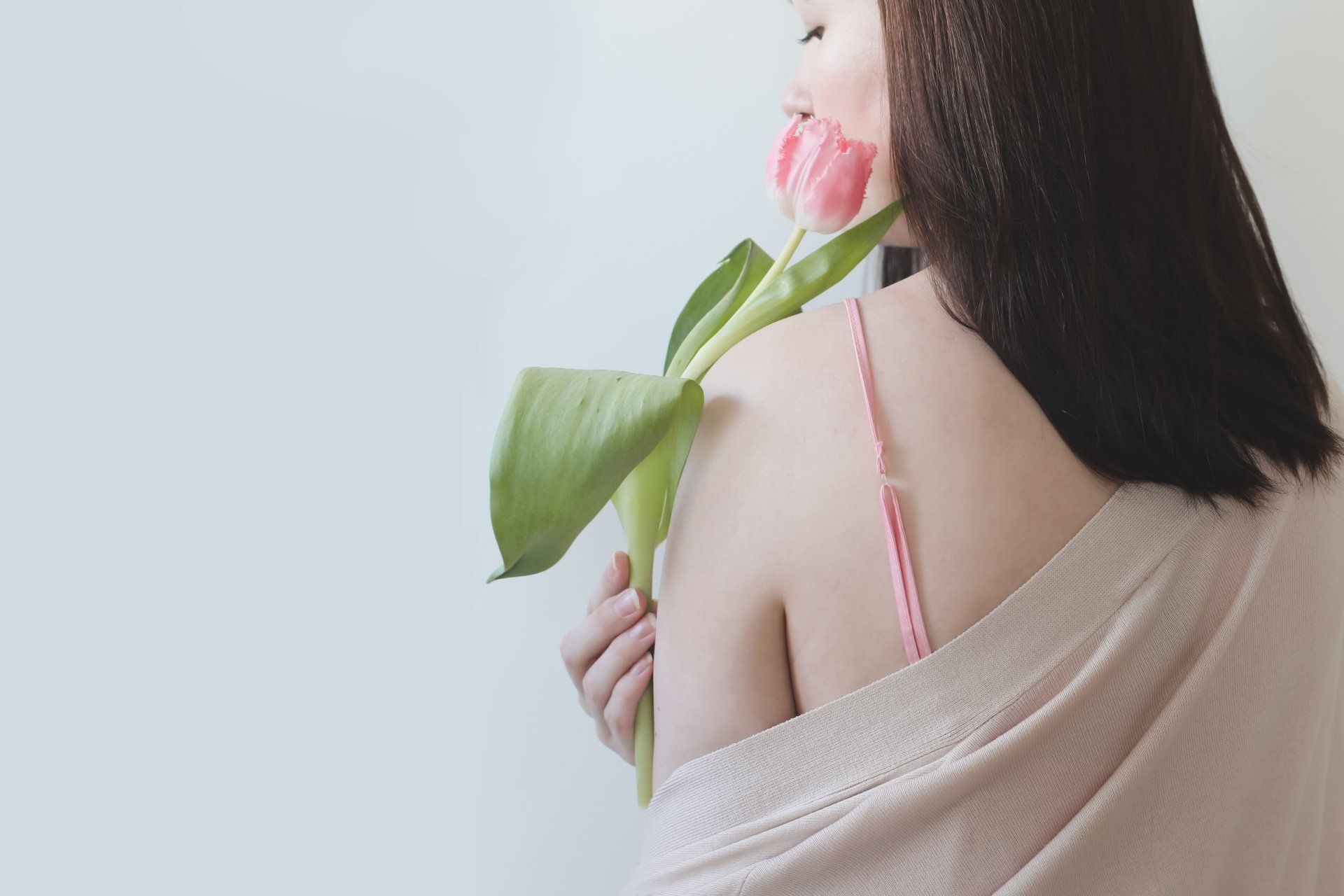 una donna con un reggiseno rosa tiene in mano un tulipano rosa