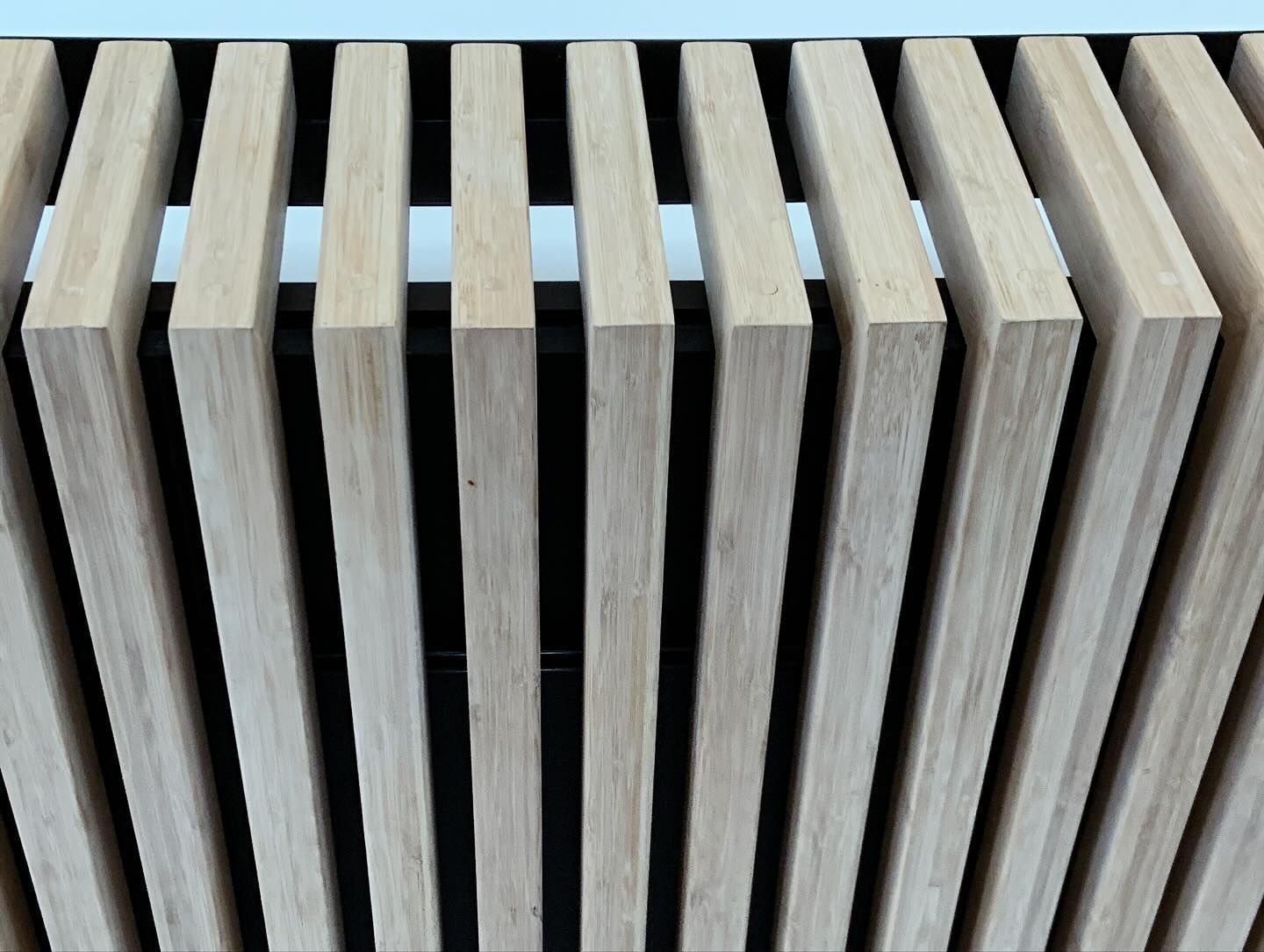 A pattern of vertical, light-toned wood slats against a recessed black background.