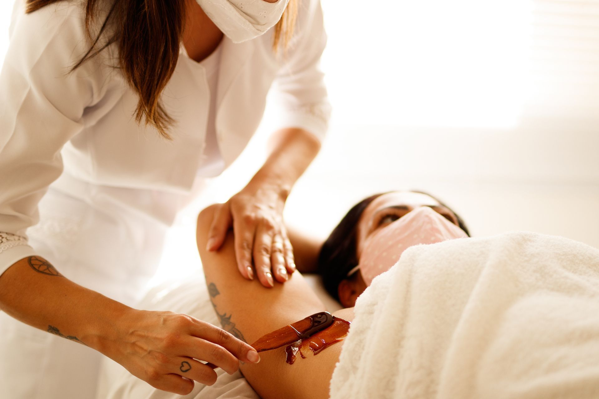 A woman wearing a mask is giving a woman a massage.