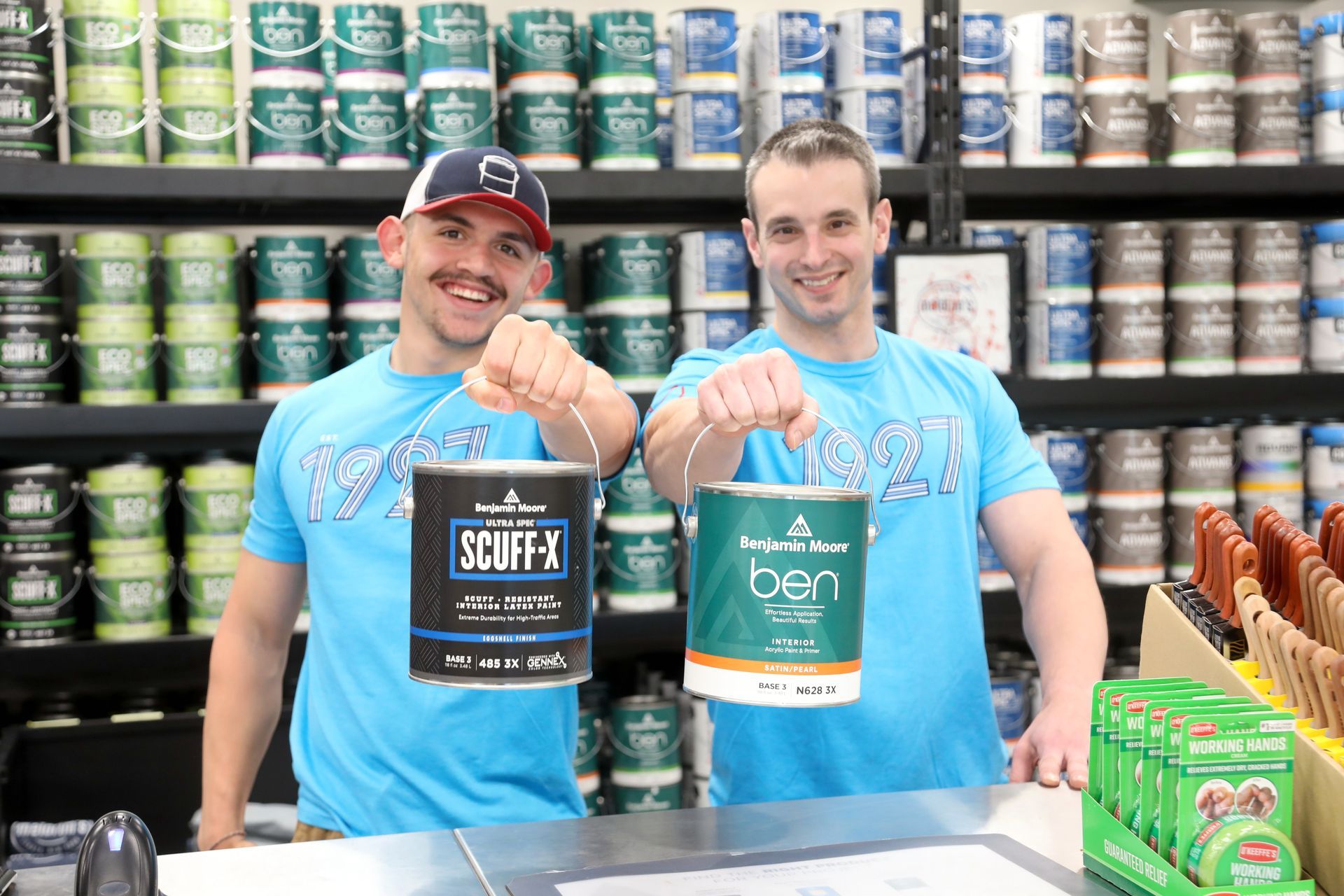 Two men are holding cans of paint in a store.