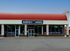 Meldrim's Paints store exterior with a curved red roof, white facade, and large glass storefront.