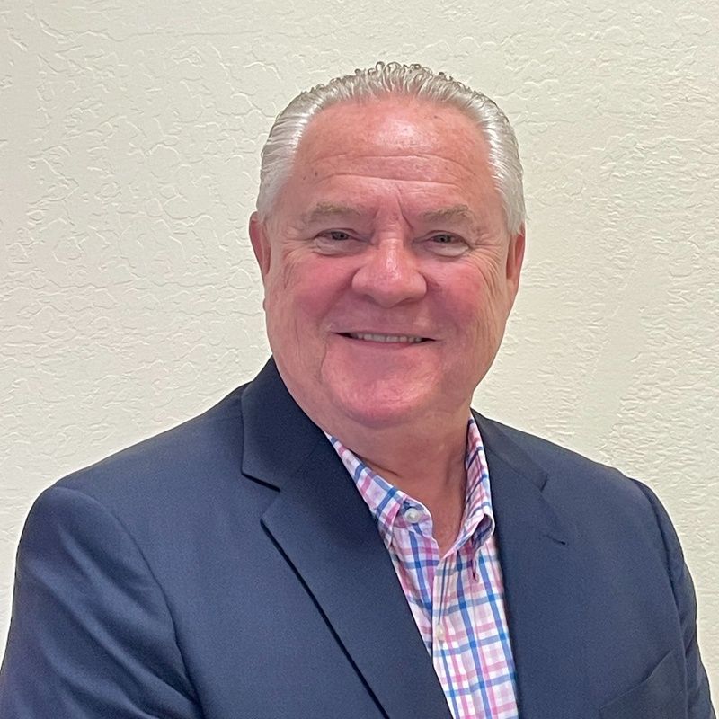 A man in a suit and plaid shirt is smiling for the camera.