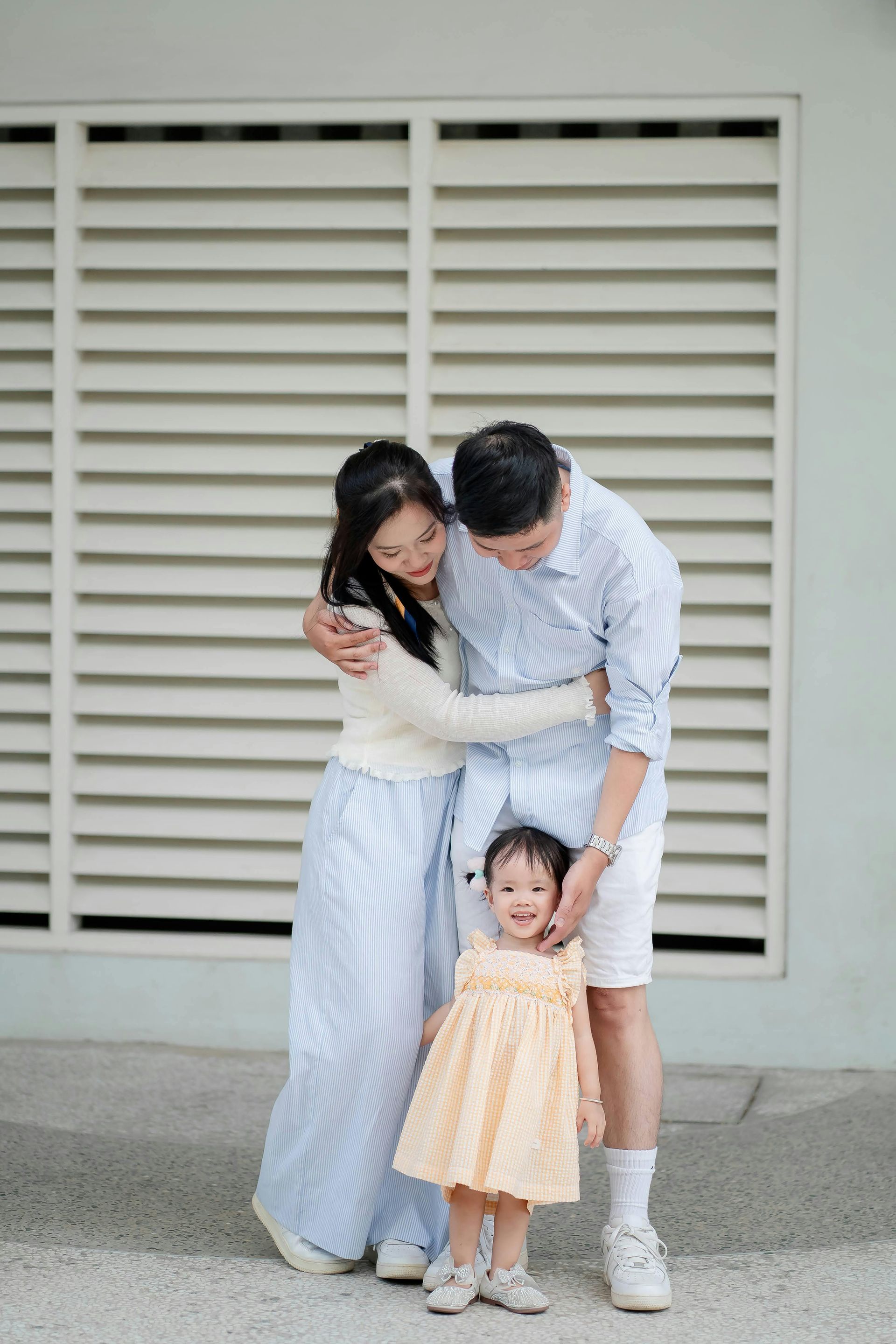 A man and woman are standing next to a little girl in front of a building.