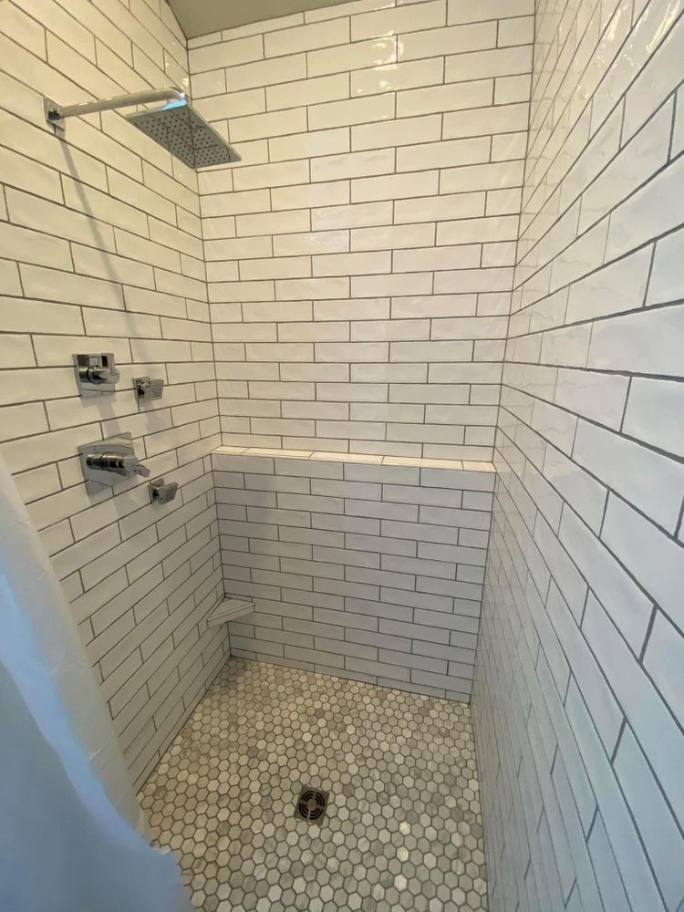 White-tiled walk-in shower with mosaic floor and chrome shower fixtures.