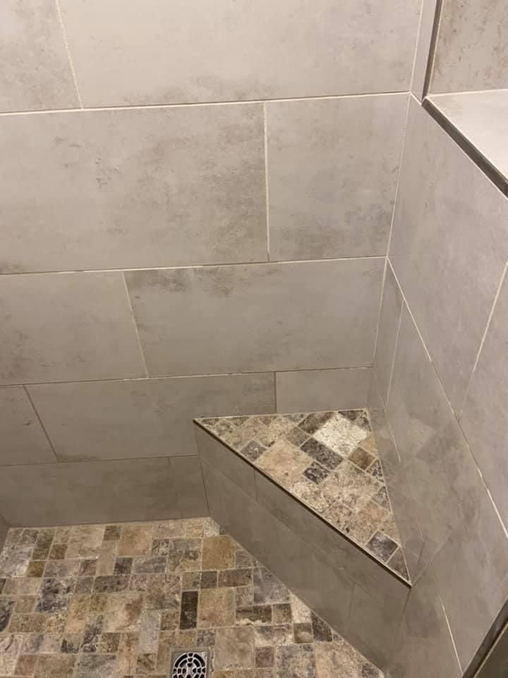 Tiled shower corner with a triangular bench and mosaic floor tiles