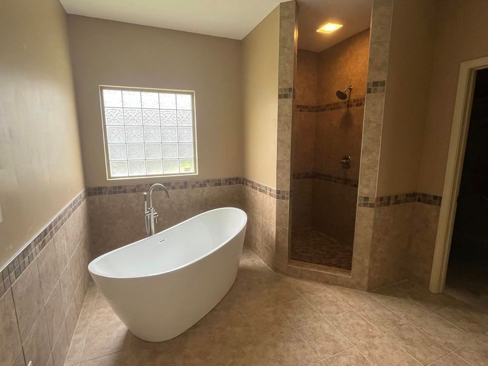 Modern bathroom with a freestanding tub, tiled walk-in shower, and window