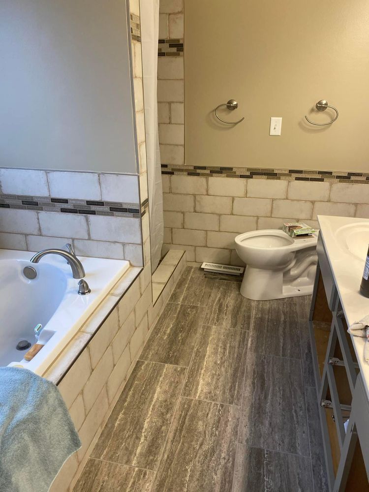 Bathroom with bathtub, toilet, and vanity in a gray tiled interior.