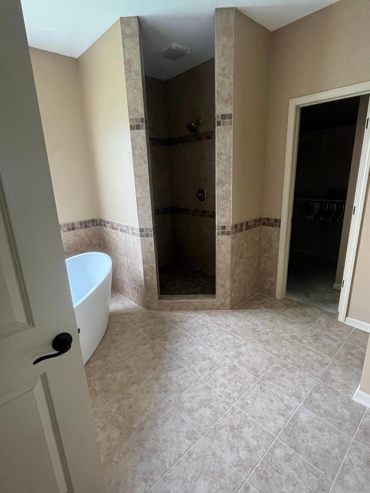 Bathroom with tiled floor, bathtub on left, shower alcove center, and open doorway on right.