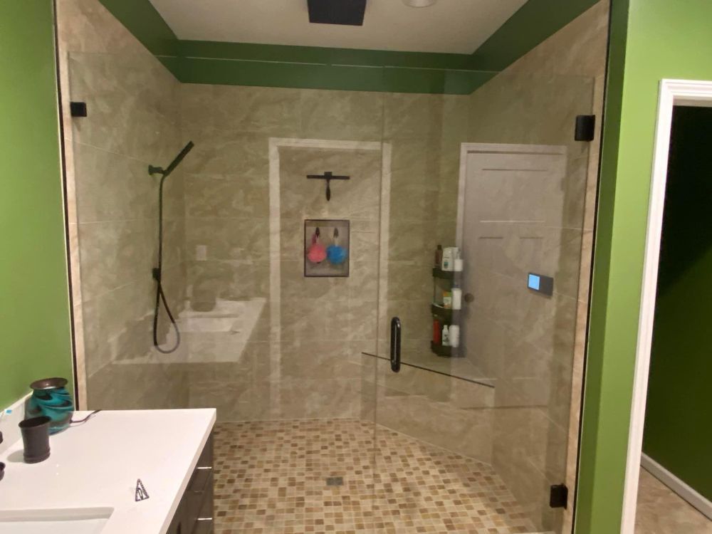 Walk-in shower with glass enclosure, beige tile, two showerheads, and a wall-mounted shelf.