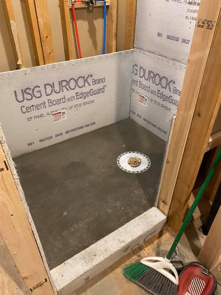 Bathroom shower under construction with cement board walls and a shower drain in the floor