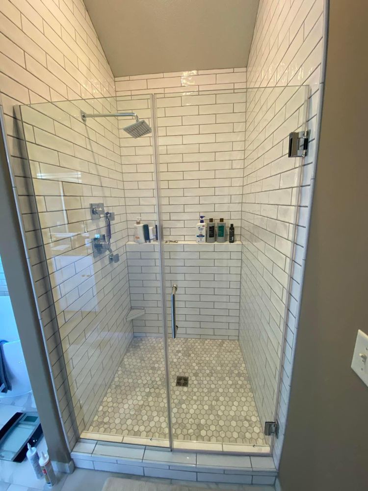 Glass-enclosed shower with white subway tile, built-in shelf, and chrome fixtures