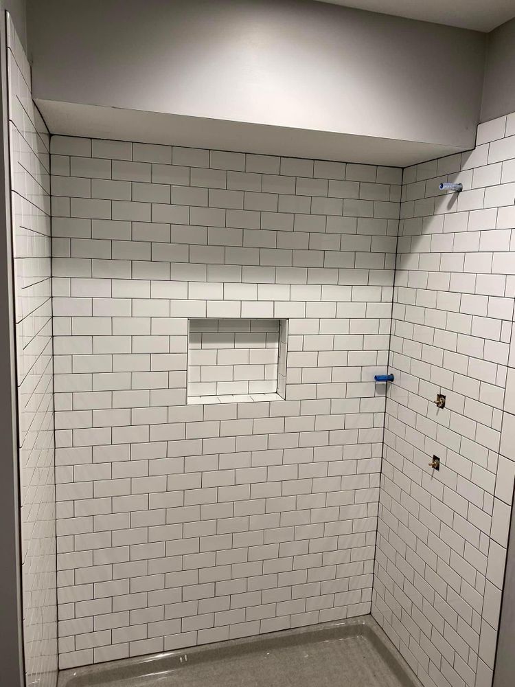 White tiled shower stall with a recessed niche and gray floor.