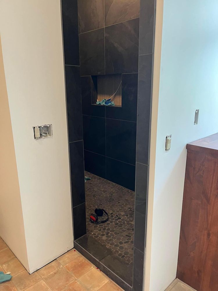 Narrow black-tiled doorway with a small wall niche in a tiled hallway or bathroom.