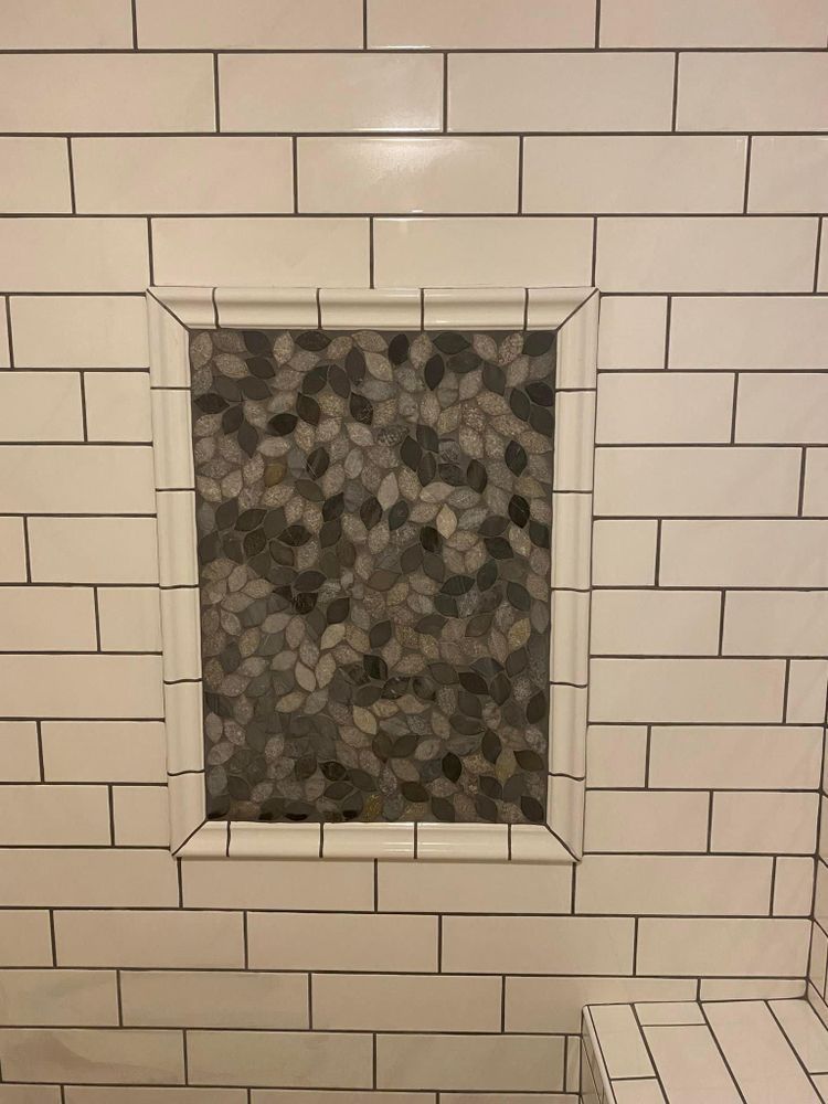 White subway tile wall with a recessed pebble-stone niche in the center