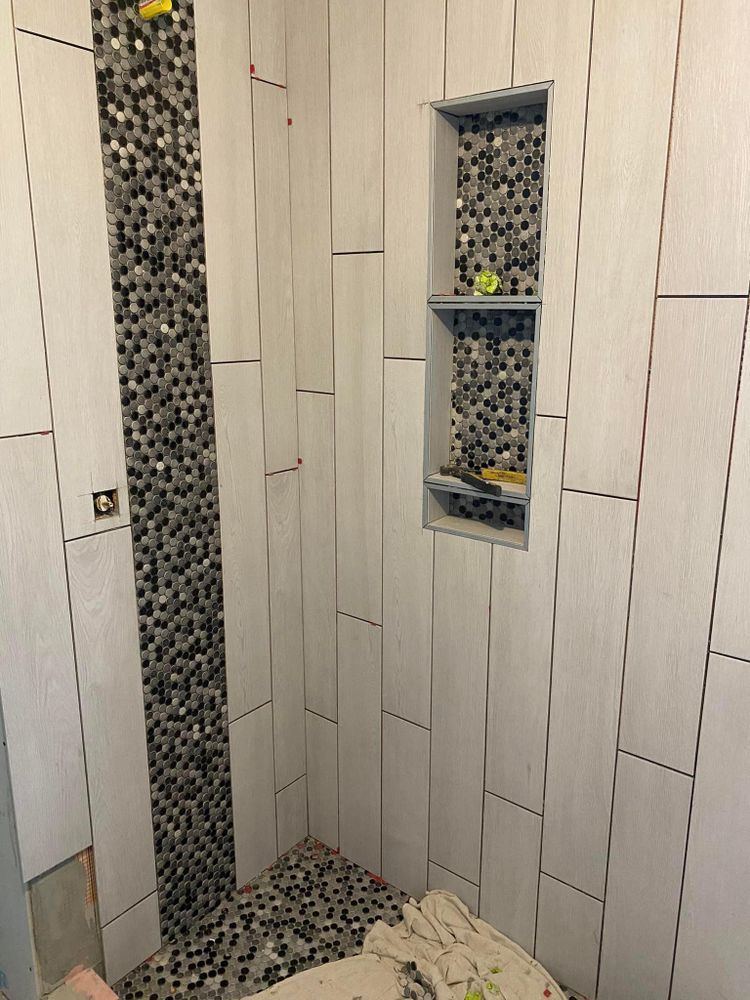 Modern shower with white tile walls, mosaic accent strip, and built-in niche holding toiletries