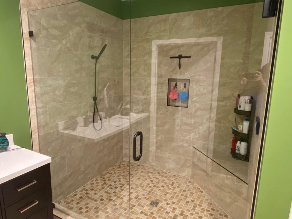 Modern tiled walk-in shower with glass door, bench, wall niche, and rainfall showerhead