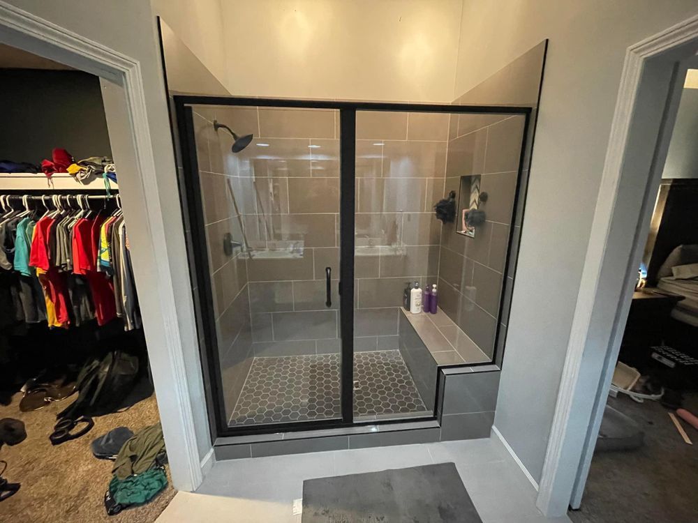 Bathroom with a black-framed glass shower enclosure and white vanity cabinet, viewed from a doorway