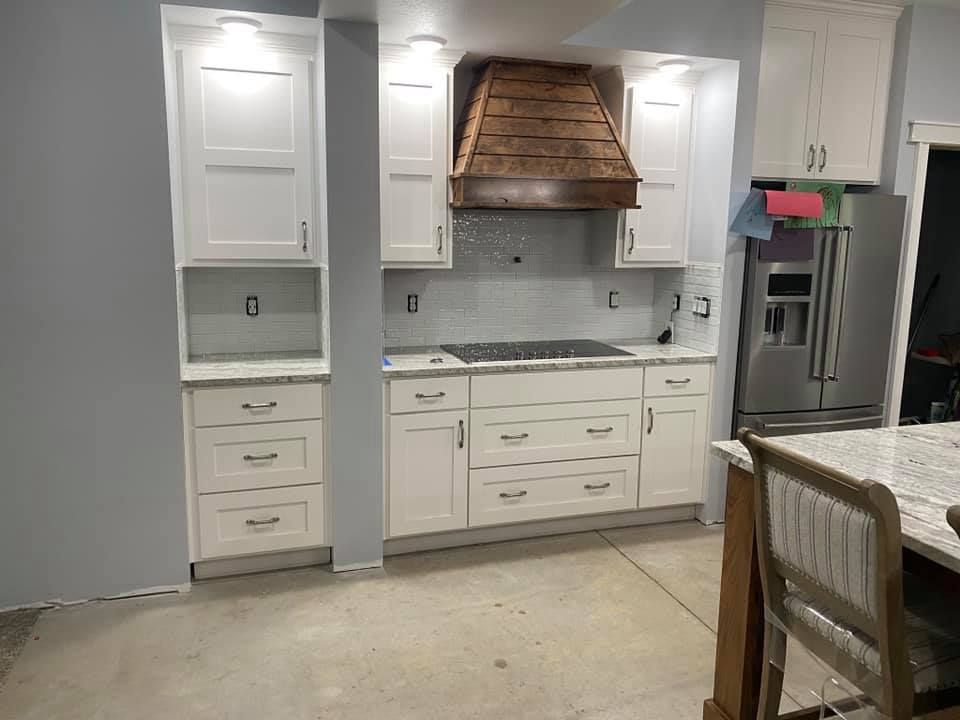 White kitchen with cabinets, copper range hood, stainless fridge, and granite island countertop